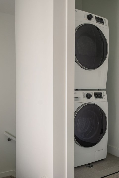 Two white front loading washing machines in a laundry room.