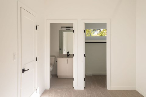 A white bathroom with a toilet, sink, and cabinet.