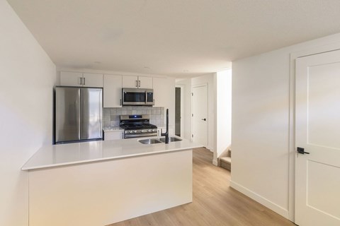 A kitchen with a refrigerator, microwave, oven, and sink.