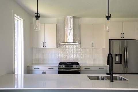 A modern kitchen with a stove, sink, and cabinets.
