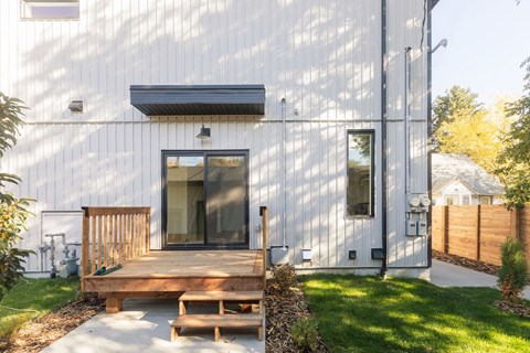 A modern house with a white exterior and a wooden deck.