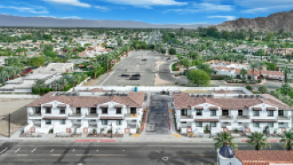 A large white building with a red roof is in the center of a parking lot.