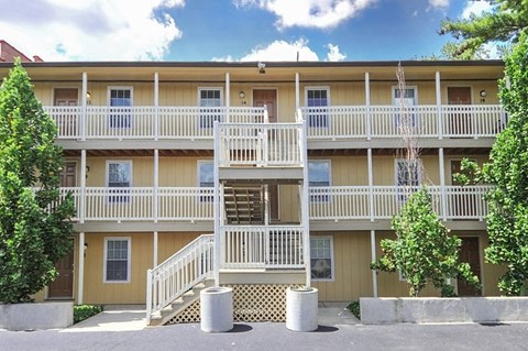 A yellow building with white railings and a staircase in front.