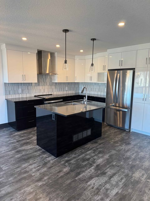 A modern kitchen with a black island and stainless steel appliances.