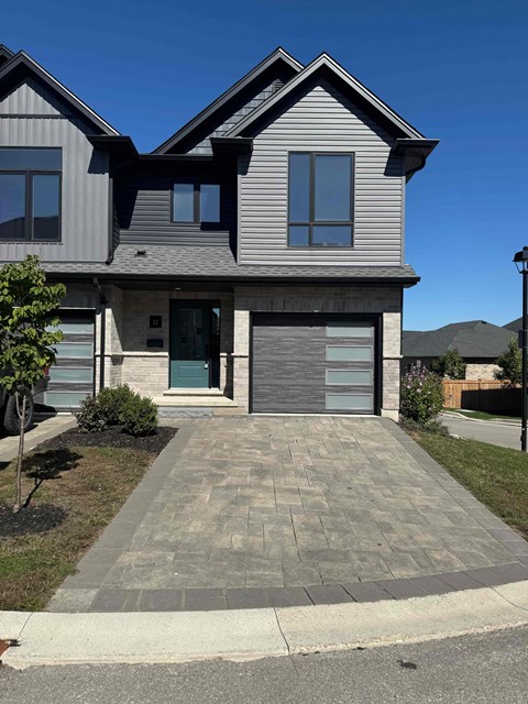 A modern house with a grey front yard and a grey driveway.