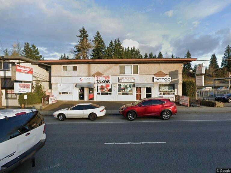A car dealership with a red car in the foreground.