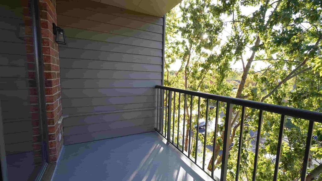 A balcony with a black railing and a brick pillar.