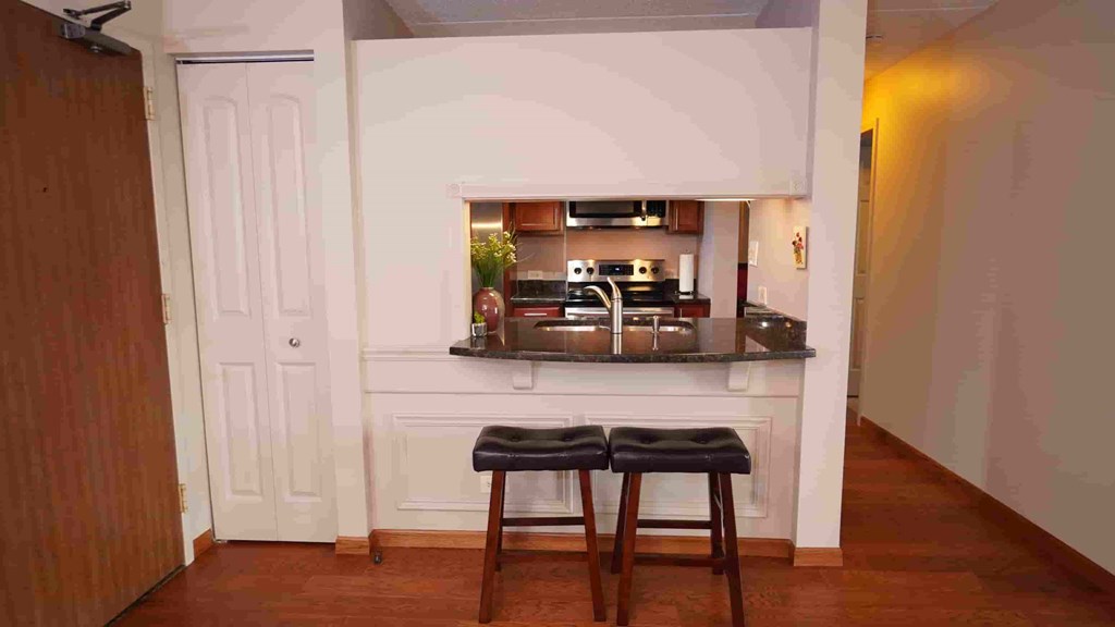 A kitchen with a white door and a counter with two stools.