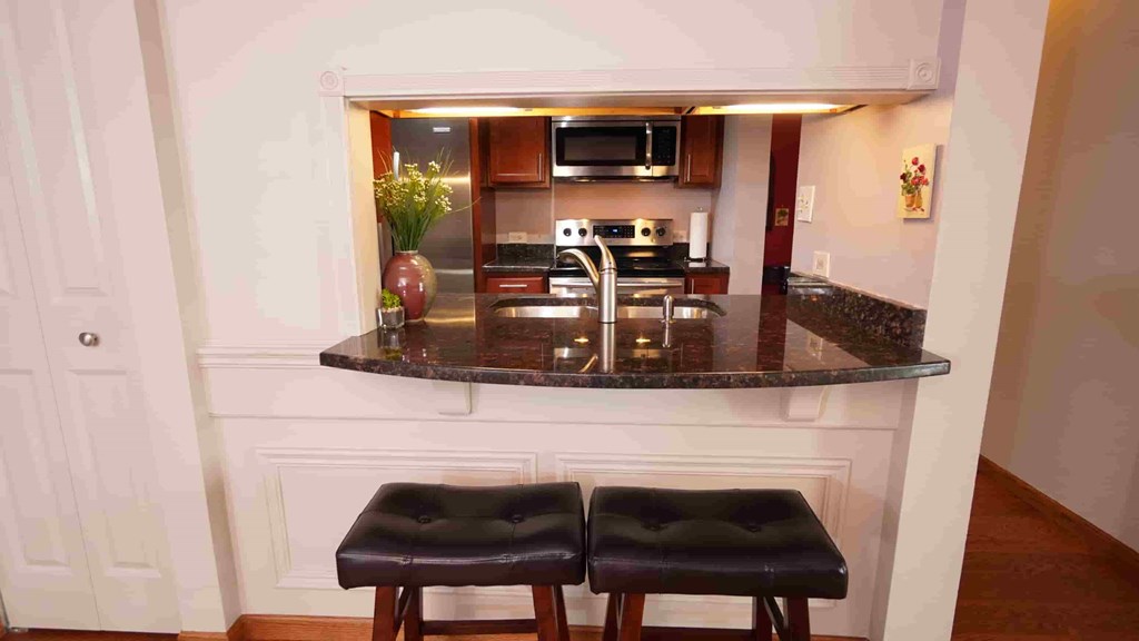 A kitchen with a bar stool in front of it.