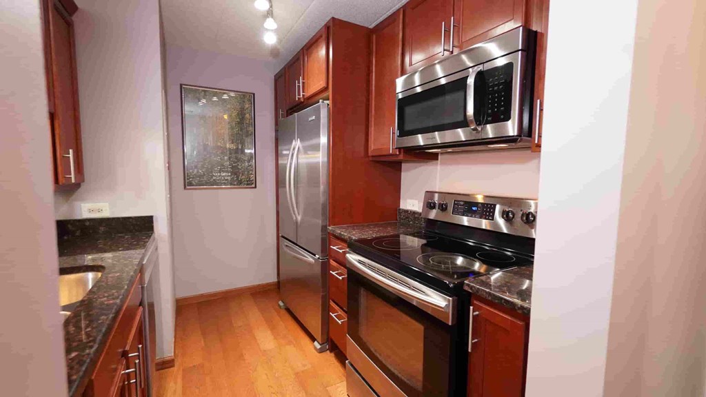 A kitchen with wooden cabinets and a stainless steel refrigerator.