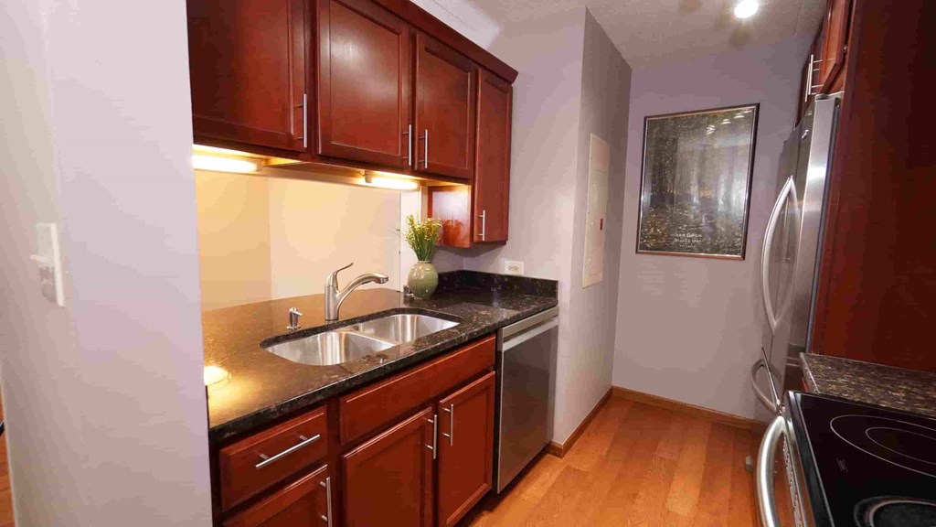 A kitchen with wooden cabinets and a stainless steel refrigerator.