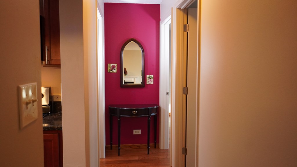 A hallway with a mirror and a table in the middle.