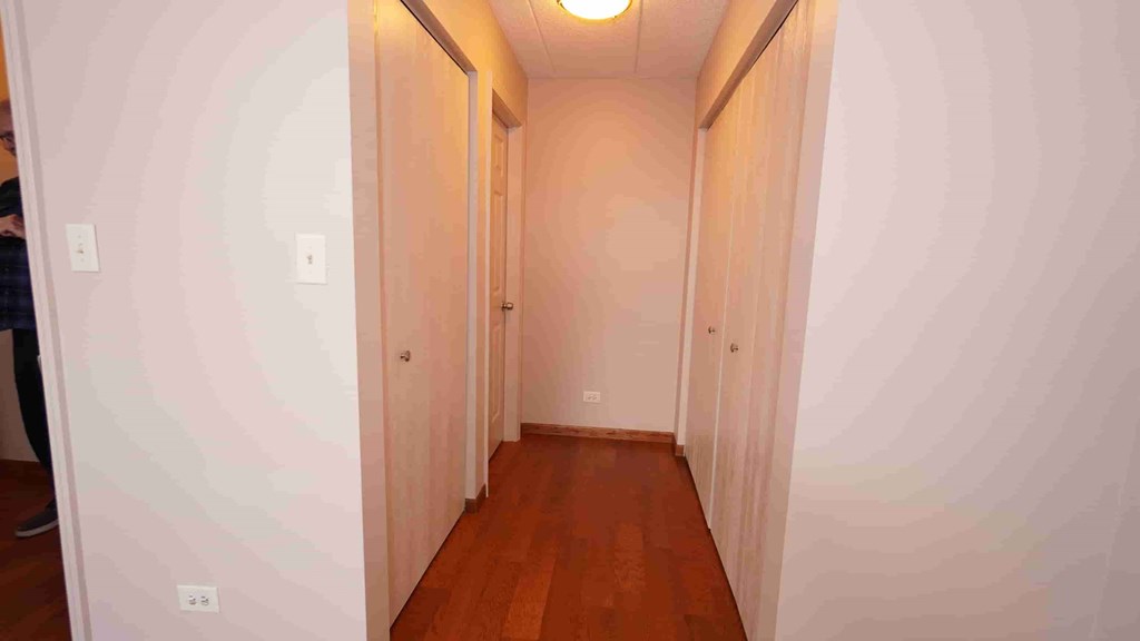 A hallway with wooden floors and white walls.