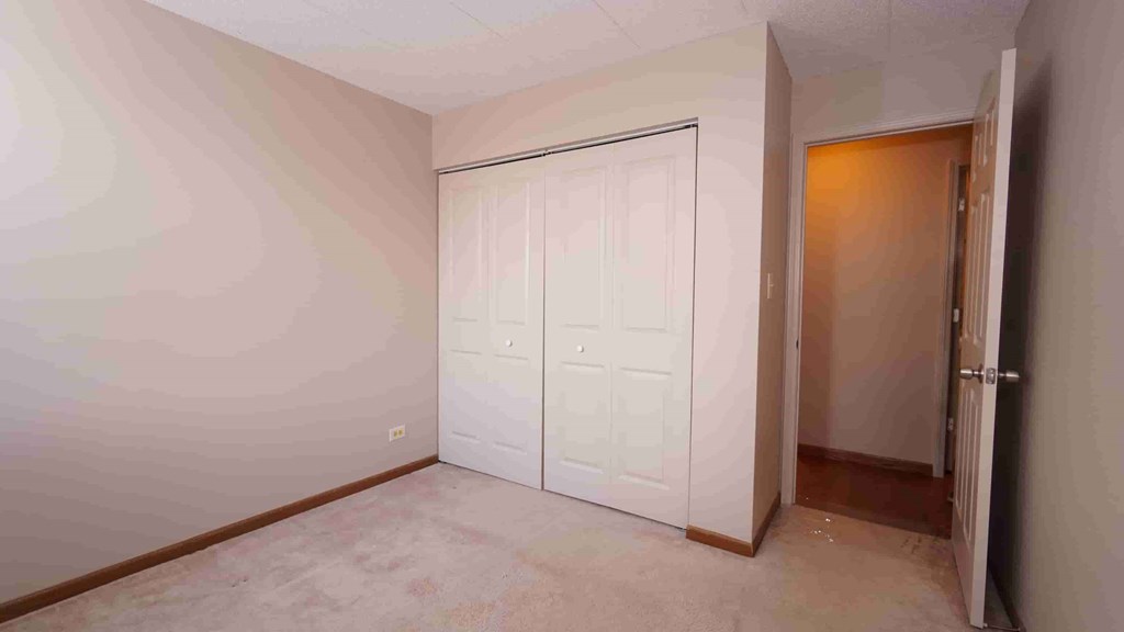 A room with a white door and a brown floor.