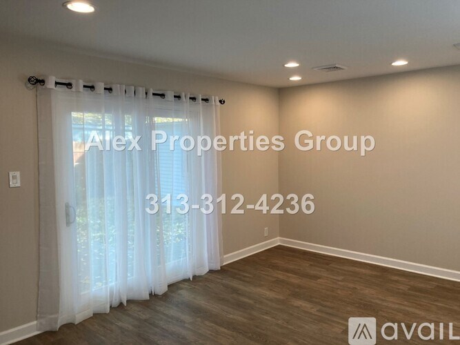 A room with a window covered by sheer curtains and a sign that says "Alex Properties Group" and a phone number.