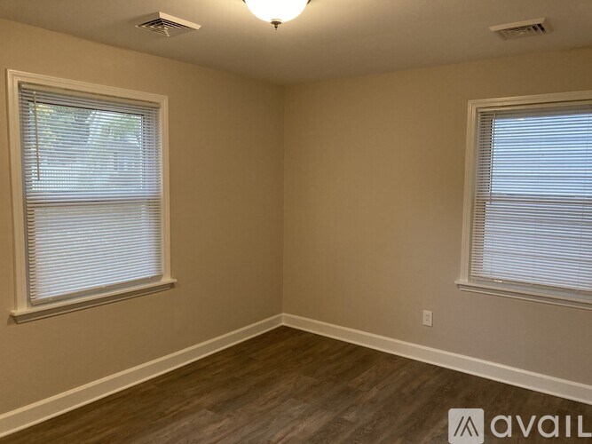A room with two windows and wooden flooring.