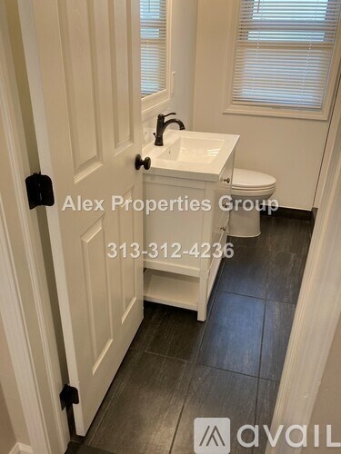 A white sink in a bathroom with a door that has a black handle.