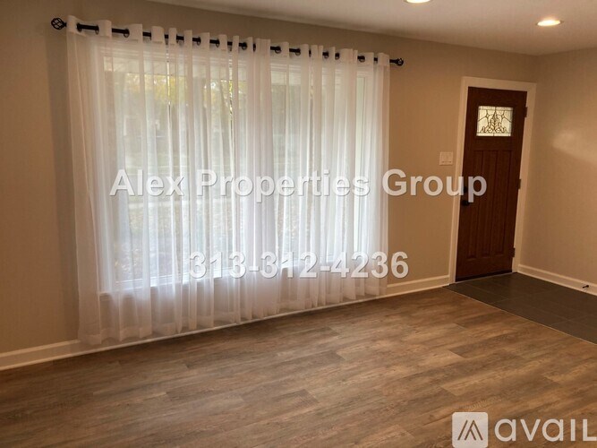 A room with a door and a window with curtains, and a sign that says Alex Properties Group.