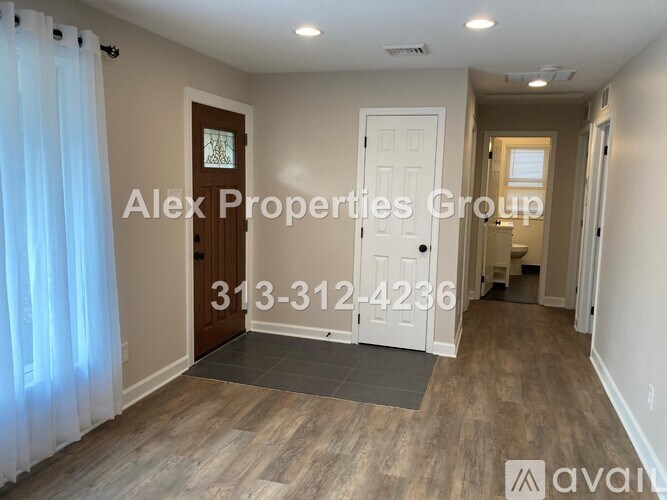 A room with a door, a window with curtains, and a wooden floor.
