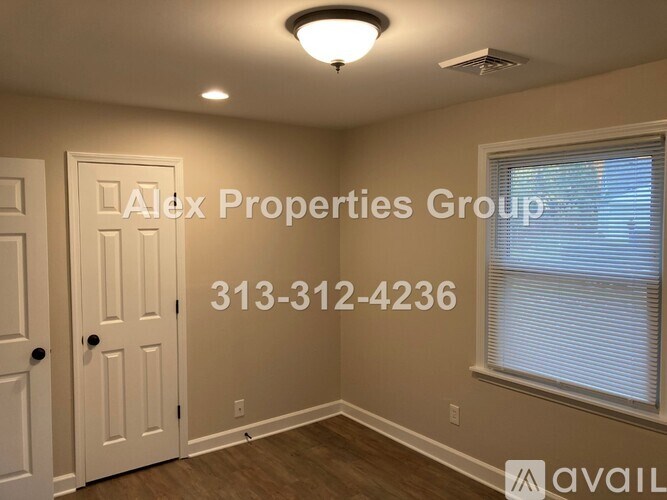 A room with a door, a window, and a light fixture on the ceiling.