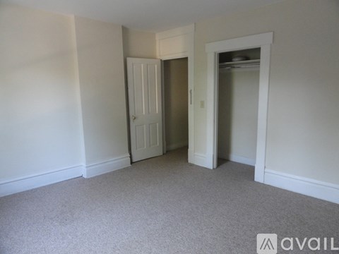 A room with a carpeted floor and two doors, one of which is open.