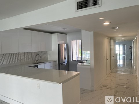 A modern kitchen with white cabinets and a marble countertop.