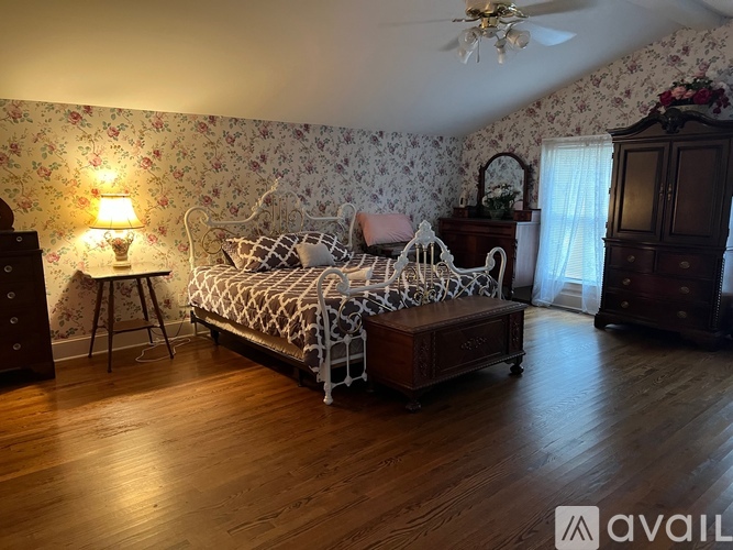 A bedroom with a bed, dresser, and a ceiling fan.
