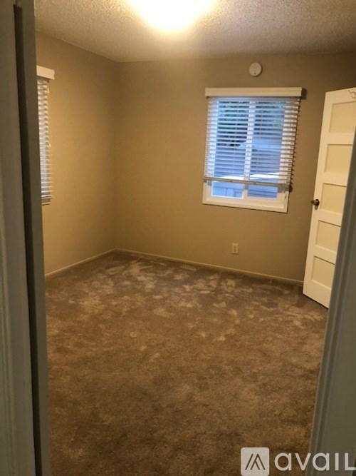 A room with a carpeted floor and a window with blinds.