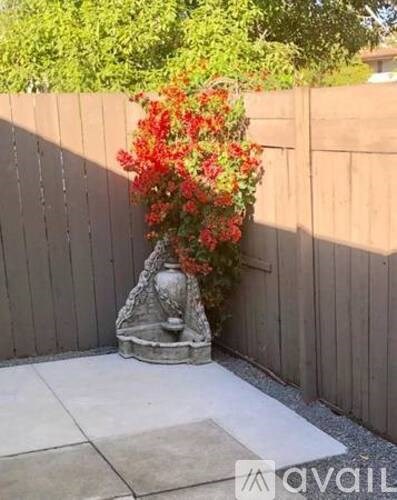A garden with a fence and a statue with flowers.