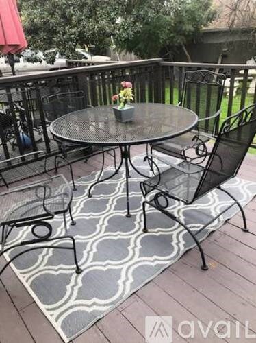 A table with chairs and a vase of flowers on a patio.