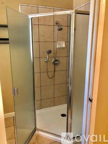 A glass shower stall with a white tub and silver frame.