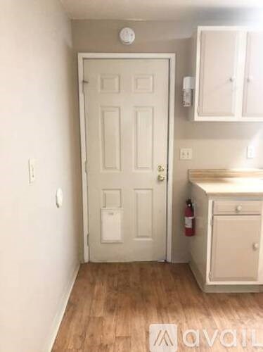 A white door with a white cabinet above it and a white wall to the left.