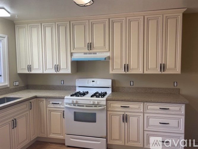 A kitchen with a white stove and cabinets.