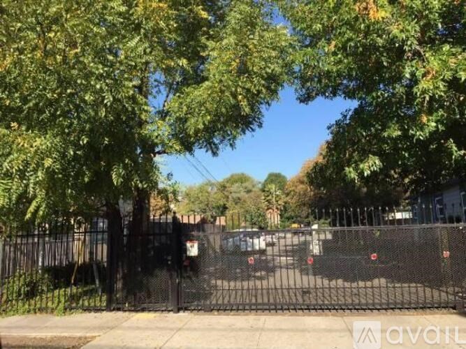A black fence with a gate blocks the view of a parking lot.