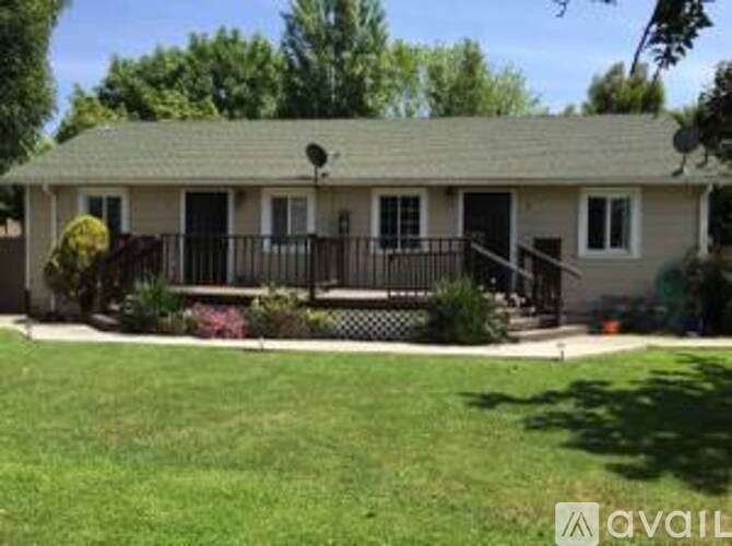 A house with a green lawn and trees in the background.