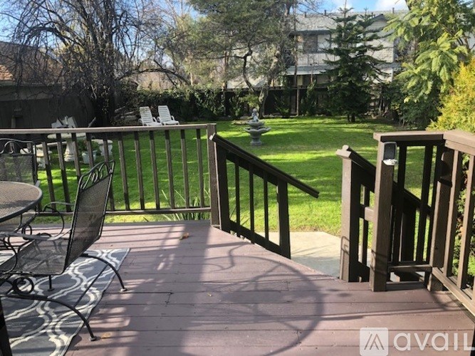 A patio with a table and chairs overlooking a green lawn.