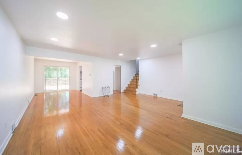 A spacious room with wooden floors and a staircase.