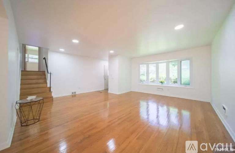 A spacious room with wooden floors and a staircase.