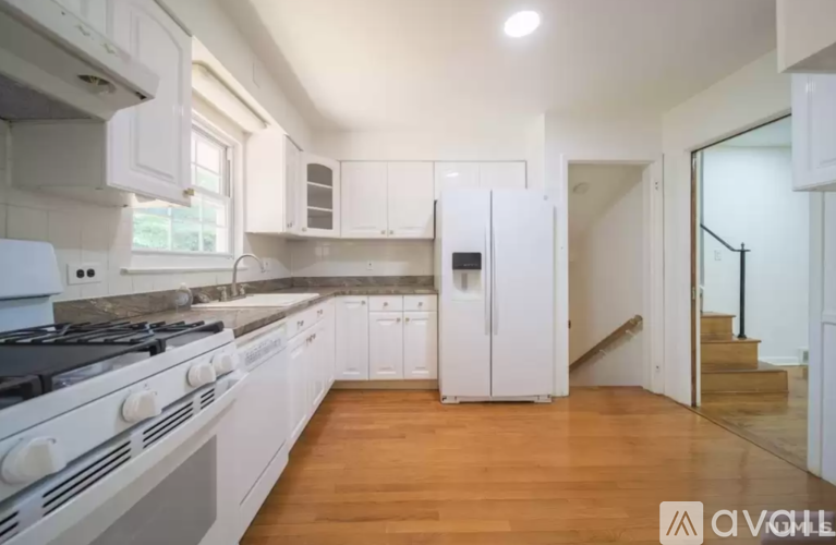 A modern kitchen with white appliances and wooden floors.