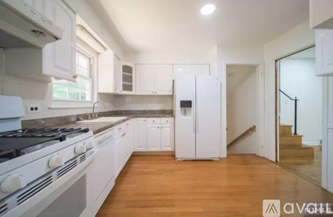A modern kitchen with white appliances and wooden floors.