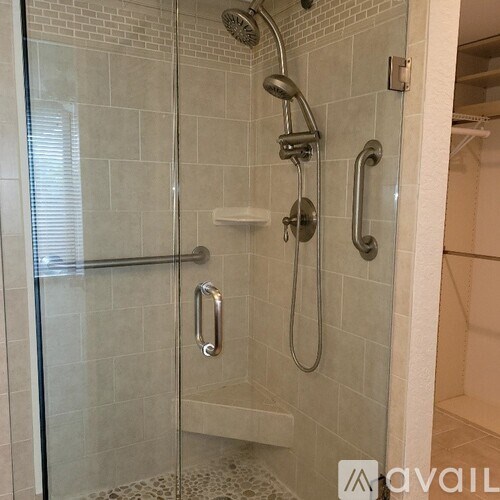 A shower area with a glass door and a chrome shower head.