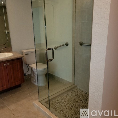A bathroom with a glass shower door and a toilet.