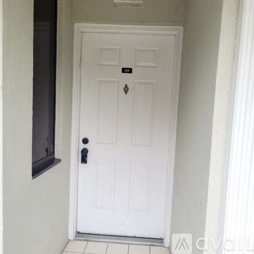 A white door with a black handle and a small black plaque above it.