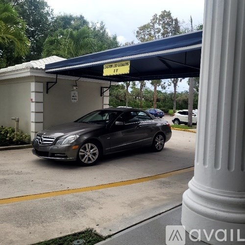 A black Mercedes is parked under a blue canopy.