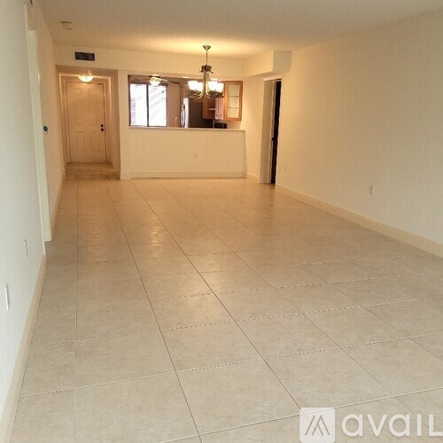 A spacious room with tiled flooring and a bar area in the background.
