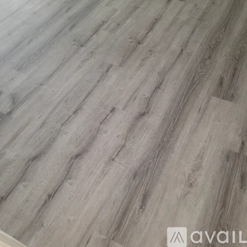 A wooden floor with a greyish tone and a logo that reads "avai" on the bottom right.