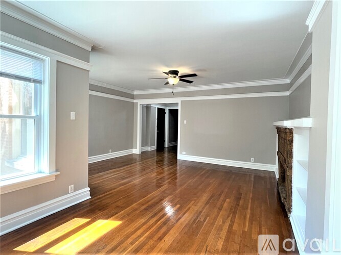 A spacious room with wood flooring and a ceiling fan.