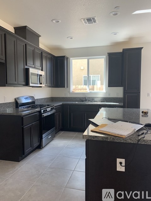 A kitchen with black cabinets and a granite countertop.