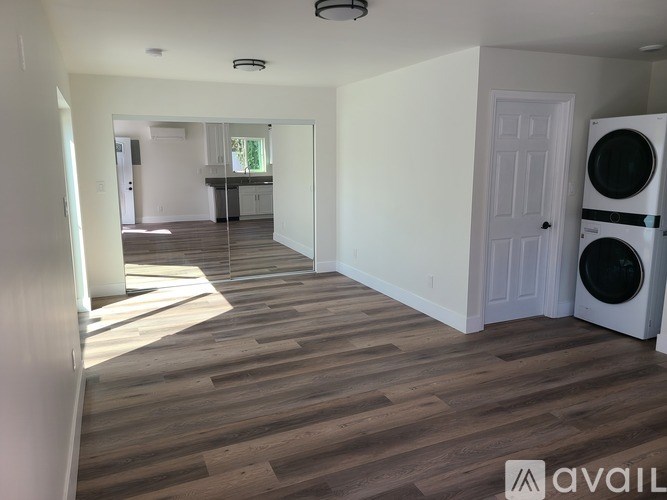 A room with wooden flooring and a washing machine in it.