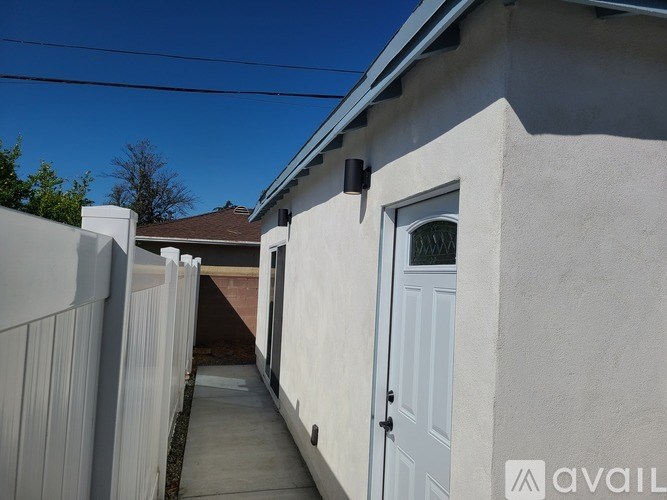 A white door is on the right side of a concrete path.